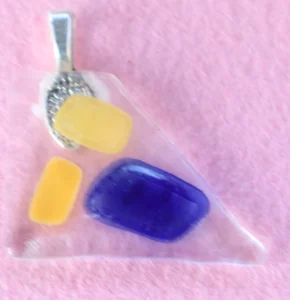 Triangle en verre transparent avec deux fragments jaune et un bleu. Une bélière collée à l'arrière.