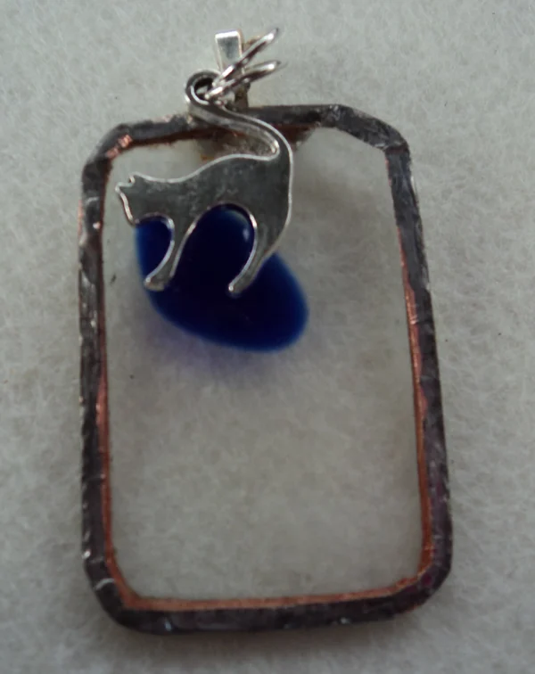 Pendentif en verre transparent avec un éclat bleu fondu. Monté en Tiffany. Une breloque en forme de chat.