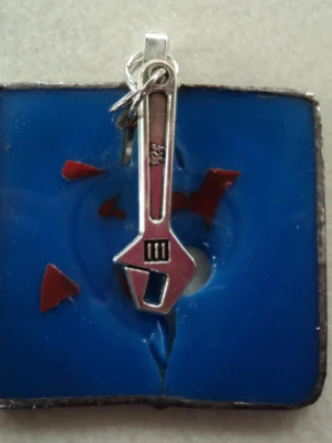 Pendentif carré en verre ébréché bleu, avec une breloque en forme de clef à molette