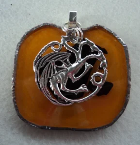 Pendentif orange avec des éclats noirs fondus en forme de pomme. Monté en Tiffany, une grande breloque en forme de dragon est suspendue.