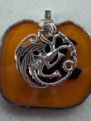 Pendentif orange avec des éclats noirs fondus en forme de pomme. Monté en Tiffany, une grande breloque en forme de dragon est suspendue.