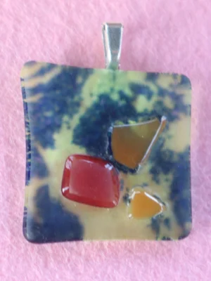 Pendentif carré fond bleu parsemé de jaune avec 3 éclats fondus rouge et orange