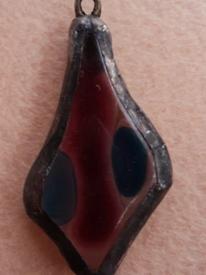 Pendentif en forme de losange irrégulier, en verre transparent, avec une lame rouge encadrée de 2 éclats bleus fondus à la surface, monté en Tiffany