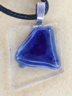 Pendentif en verre transparent avec un important éclat bleu fondu à la surface. Une bélière collée à l'arrière.