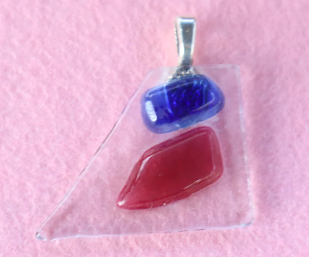 Pendentif en forme de triangle au sommet tronqué en verre transparent avec un éclat bleu et un rouge fondus