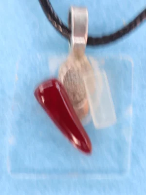 Petit pendentif en verre fin avec un éclat blanc et un rouge. Une bélière argentée collée à l'arrière.