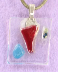 Pendentif en verre transparent avec des éclats de verre rouge et bleu fondus