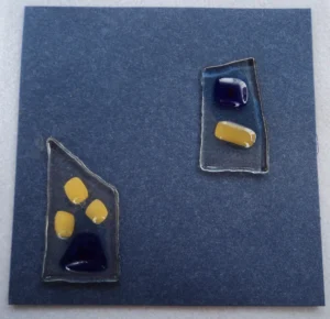 Carte postale bleu métallique avec deux fragments de verre transparent. Des fragments beige et bleu sont fondus.