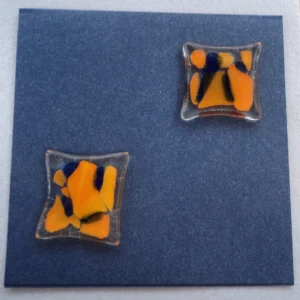 Deux carrés de fusing orange et bleu sur verre transparent, collés sur une carte en carton