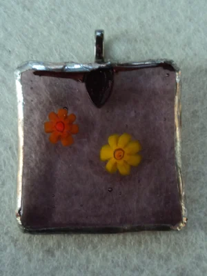 Pendentif carré en verre mauve transparent avec 2 millefioris fondus, un millefiori jaune et un orange, montés en Tiffany