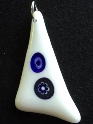 Pendentif triangulaire en verre blanc avec 2 millefioris bleus et blancs étirés par la fusion. Un anneau argenté passé dans un orifice au sommet