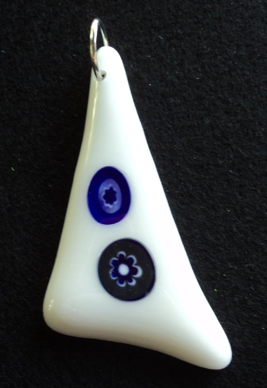 Pendentif triangulaire en verre blanc avec 2 millefioris bleus et blancs étirés par la fusion. Un anneau argenté passé dans un orifice au sommet