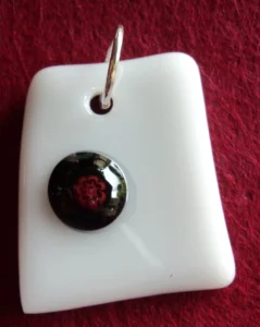 Pendentif en verre blanc avec un millefiori noir au cœur rouge