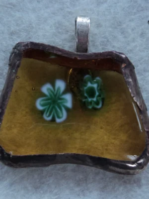 Pendentif fusing composé de 2 millefioris verts et blancs fondus sur un trapèze de verre orange transparent, monté en Tiffany avec une bélière argenté soudée à l'arrière