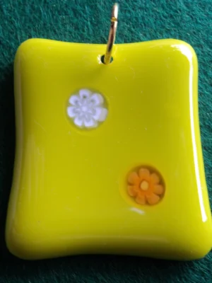 Pendentif en verre jaune avec un millefiori blanc et un orange. Un anneau doré pour la fixation