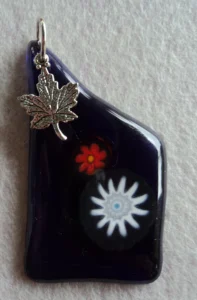 Pendentif en verre bleu nuit avec 1 millefiori blanc et 1 orange, une breloque en forme de feuille