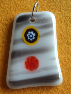 Pendentif en forme de trapèze en verre blanc strié de gris, 2 millefioris, un bleu et un orange, sont fondus à la surface