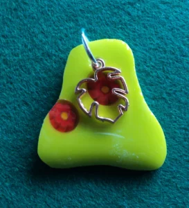 Pendentif de forme irrégulière en verre jaune avec 2 millefioris vermillons fondus et une breloque cuivrée en forme de feuille