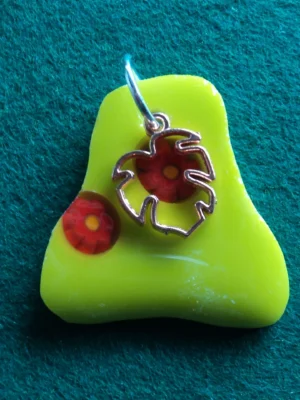 Pendentif de forme irrégulière en verre jaune avec 2 millefioris vermillons fondus et une breloque cuivrée en forme de feuille