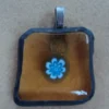 Pendentif composé d'un millefiori bleu et blanc sur verre orange transparent, monté selon la technique Tiffany