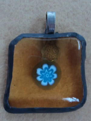 Pendentif composé d'un millefiori bleu et blanc sur verre orange transparent, monté selon la technique Tiffany