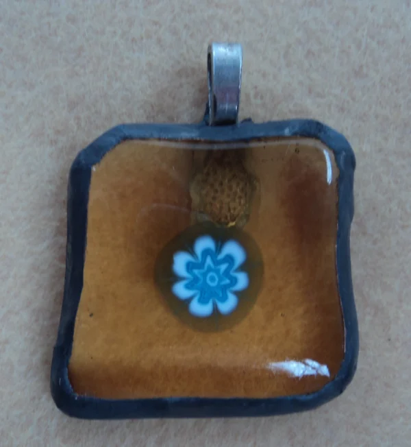 Pendentif composé d'un millefiori bleu et blanc sur verre orange transparent, monté selon la technique Tiffany