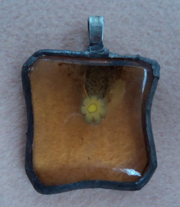 Pendentif avec un simple millefiori jaune sur fond orange transparent, monté en Tiffany