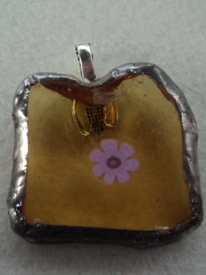 Pendentif avec un millefiori rose fondu sur verre orange transparent, monté en Tiffany