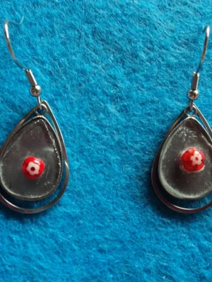 Des boucles d'oreilles composées de millefioris colorés, fondus sur du verre récupéré sur des sous-verres cassés. Monture en métal argenté inoxydable.