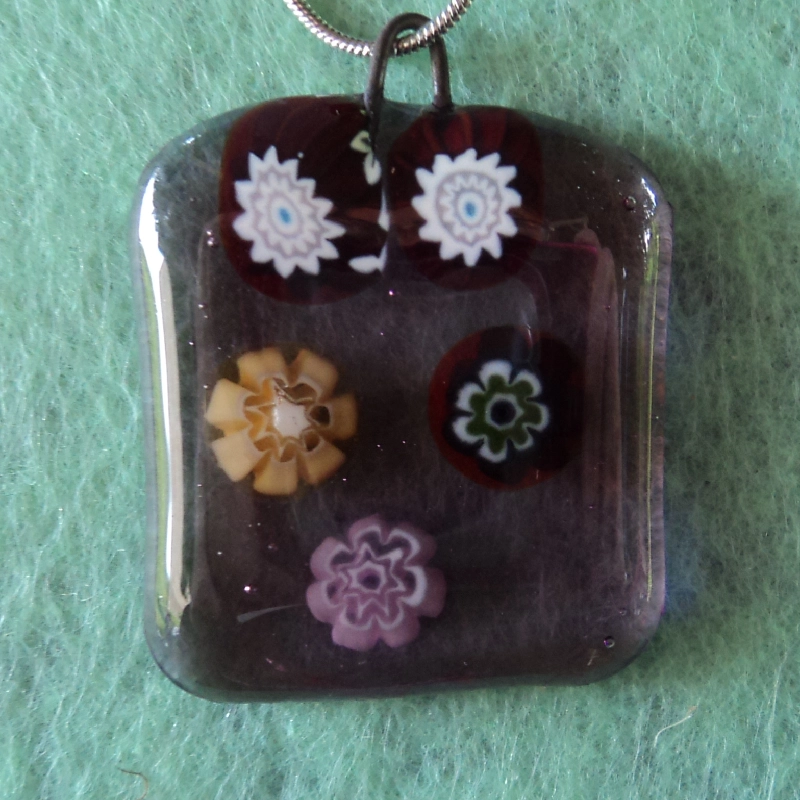 Pendentif en verre mauve semi transparent avec 5 millefioris multicolores.