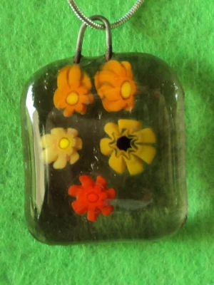 Pendentif en verre mauve semi transparent avec 5 millefioris jaune et orangé.