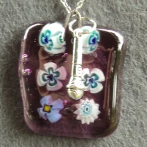 Pendentif en verre mauve semi-transparent avec 6 millefioris blanc et bleu et une breloque micro.