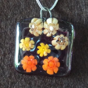 Pendentif en verre semi transparent mauve avec 7 millefioros jaune et orange fondus.