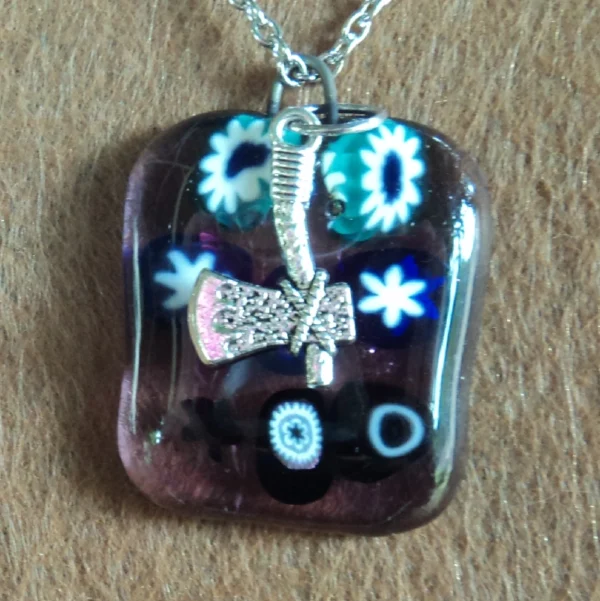 Pendentif en verre mauve semi transparent avec 8 millefioris bleu et blanc et une breloque hache