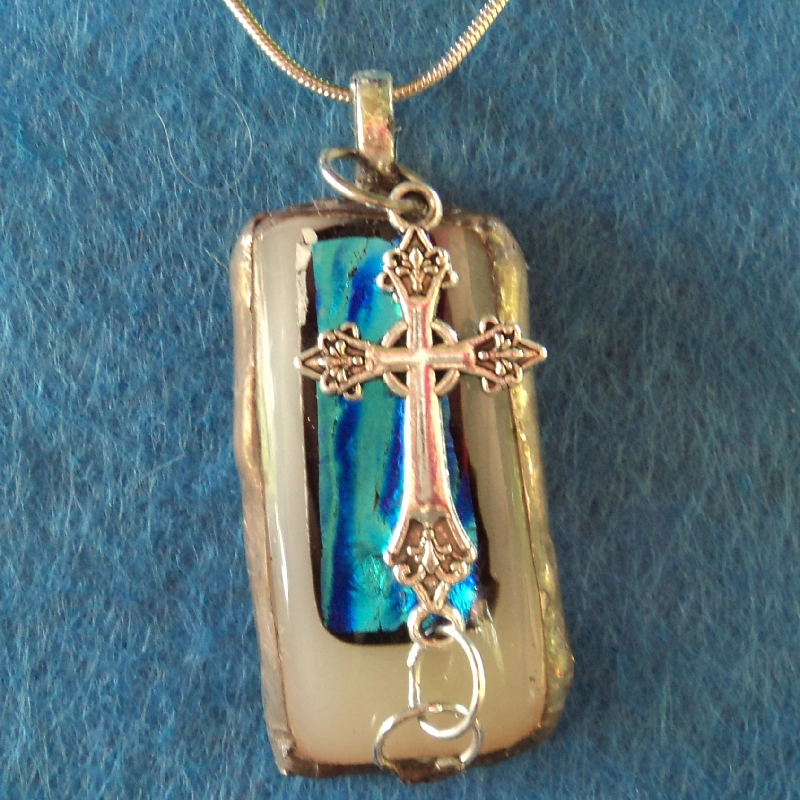 Pendentif en verre dichroïque beige et bleu turquoise avec une breloque croix